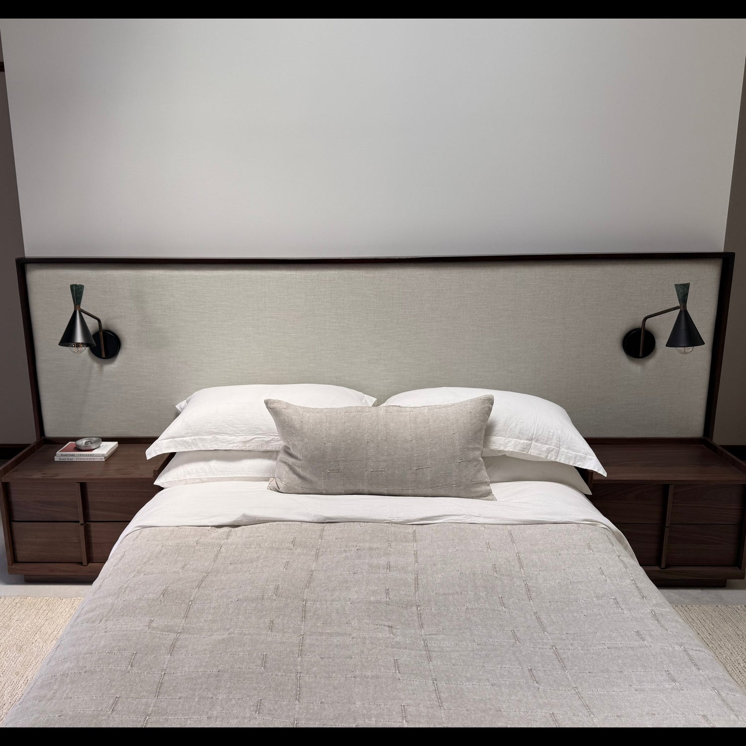 Modern bedroom with a bed, nightstands, and wall lamps.